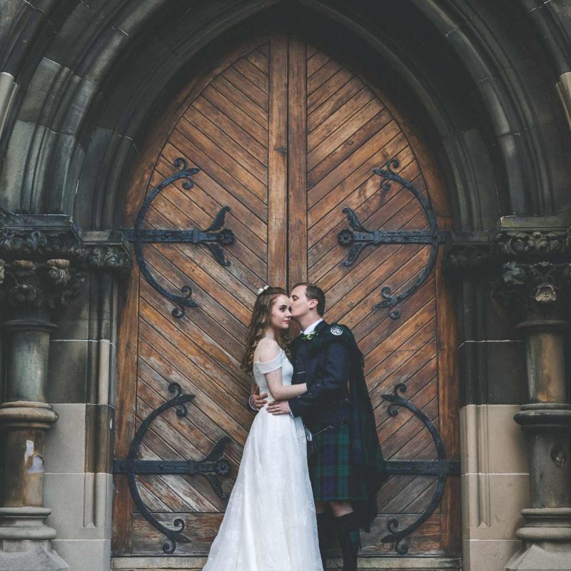 Cottiers Weddings — Bride and groom share a tender moment in front of the venue doors